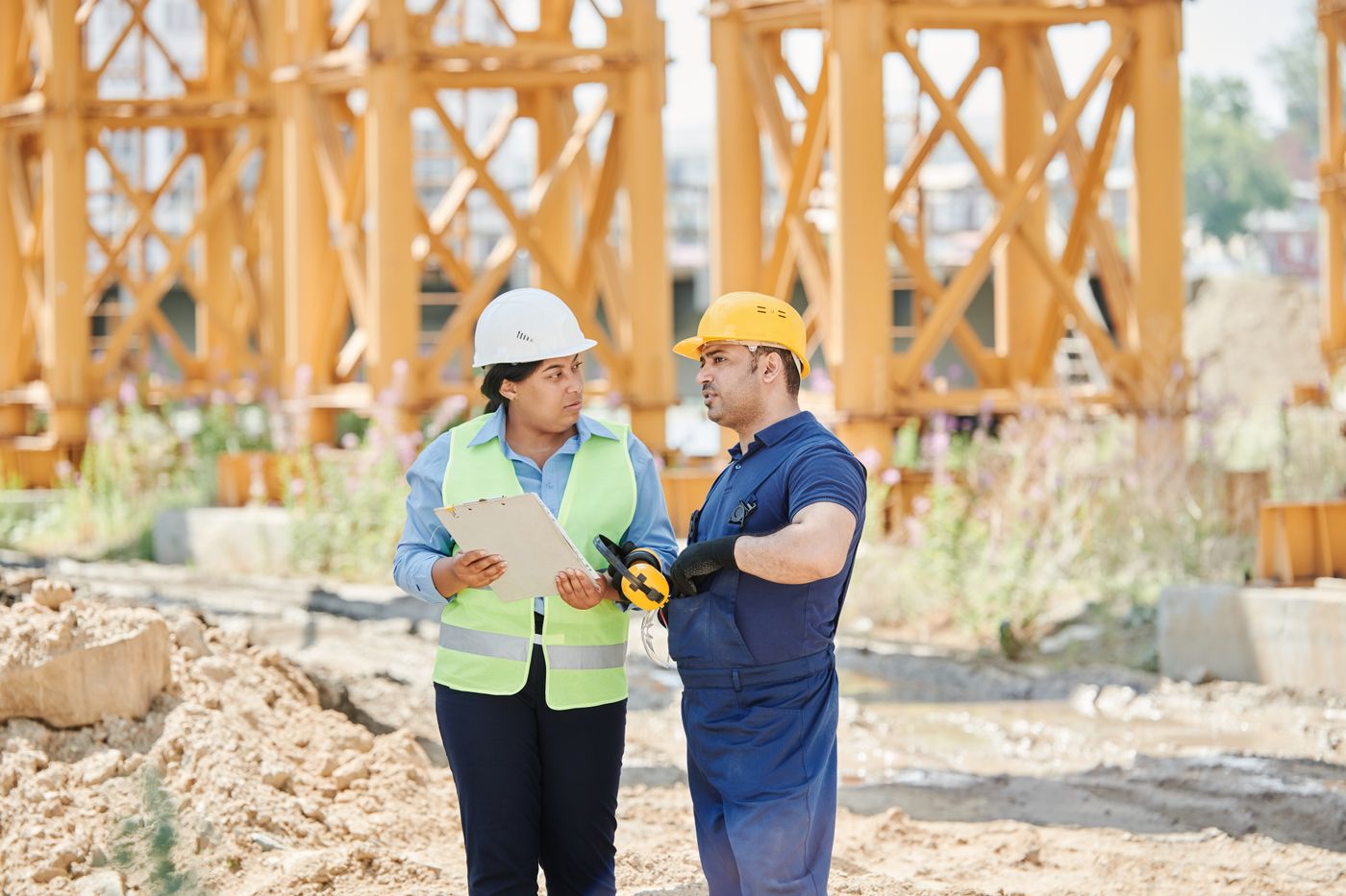 Two officers in safety vests checking a tablet on site